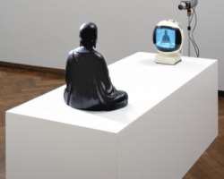 Nam June Paik, a statue of 18th century Buddha is placed opposite a camera and screen which gives a hint about the television era where everyone wants